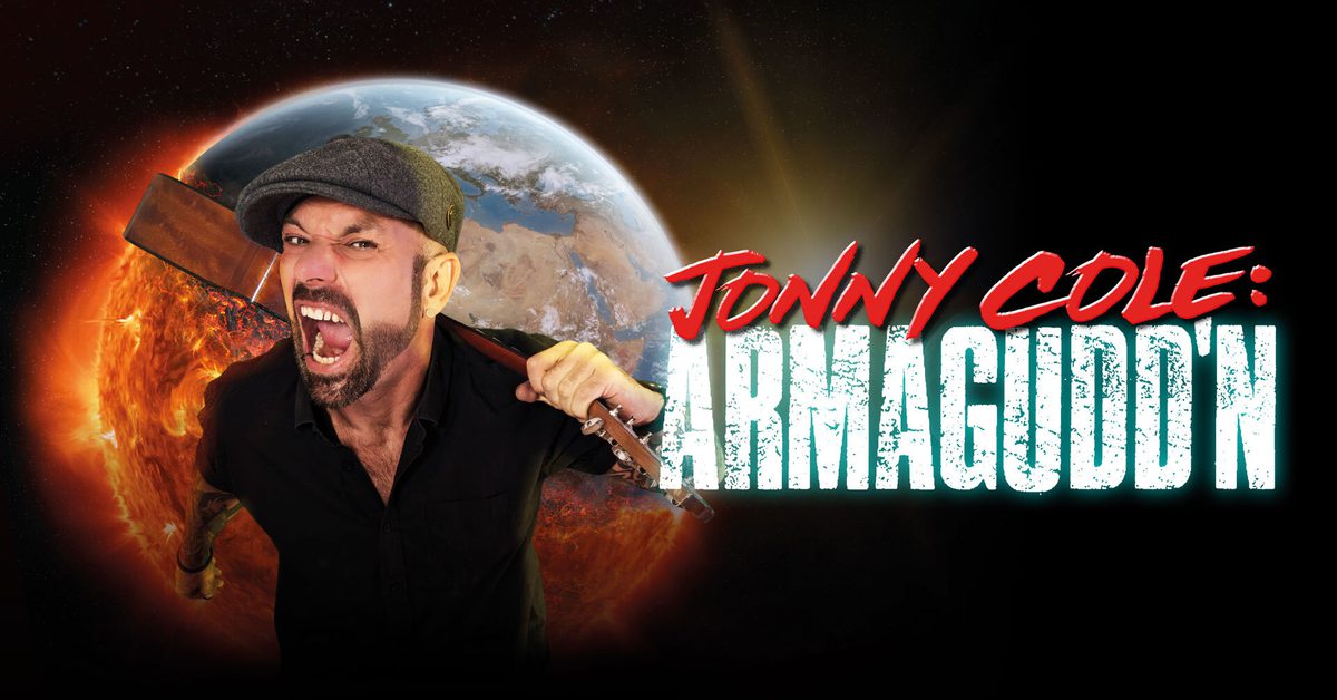 Promotional image for comedian Jonny Cole's show "Armagodd'n". A bearded white man wearing a grey flat cap and black shirt stands against a dramatic space backdrop featuring Earth and an exploding sun. He is screaming with his mouth wide open whilst resting a sledgehammer across his shoulders. The show title "JONNY COLE: ARMAGODD'N" appears to the right in red and white bold lettering.
