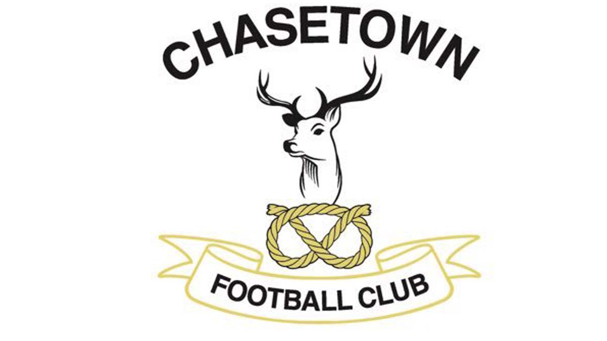 Circular badge logo for Chasetown Football Club. A white stag's head with antlers is depicted above a football, on a dark navy background. The club name "CHASETOWN FOOTBALL CLUB" arcs around the badge in white text.